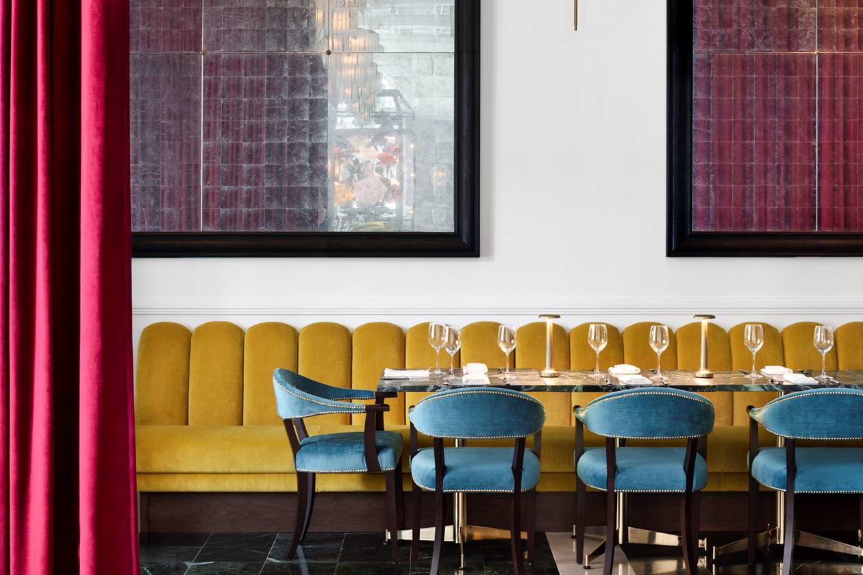 A semi-private dining room with blue chairs and a yellow sofa set for an intimate event with elegant table setting.