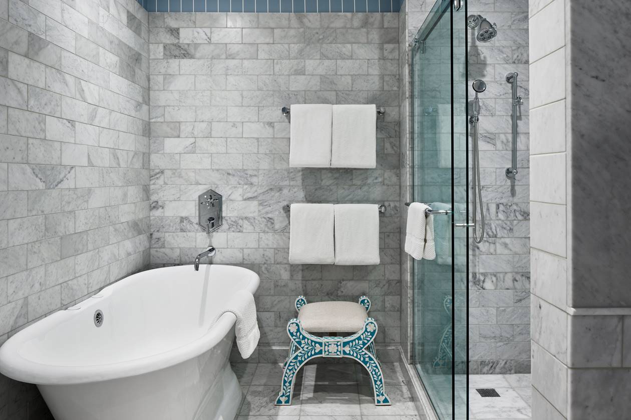 A white bathtub in the Caroline Harrison suite's gorgeous bathroom, featuring modern design and luxurious tiled fixtures.