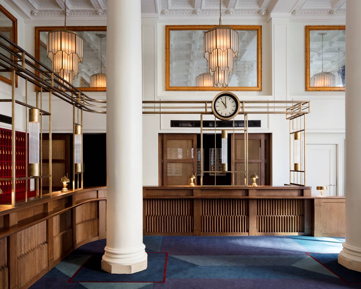 The stylish and elegant wooden reception desk at Riggs DC with white columns, grand lamps and a clock.
