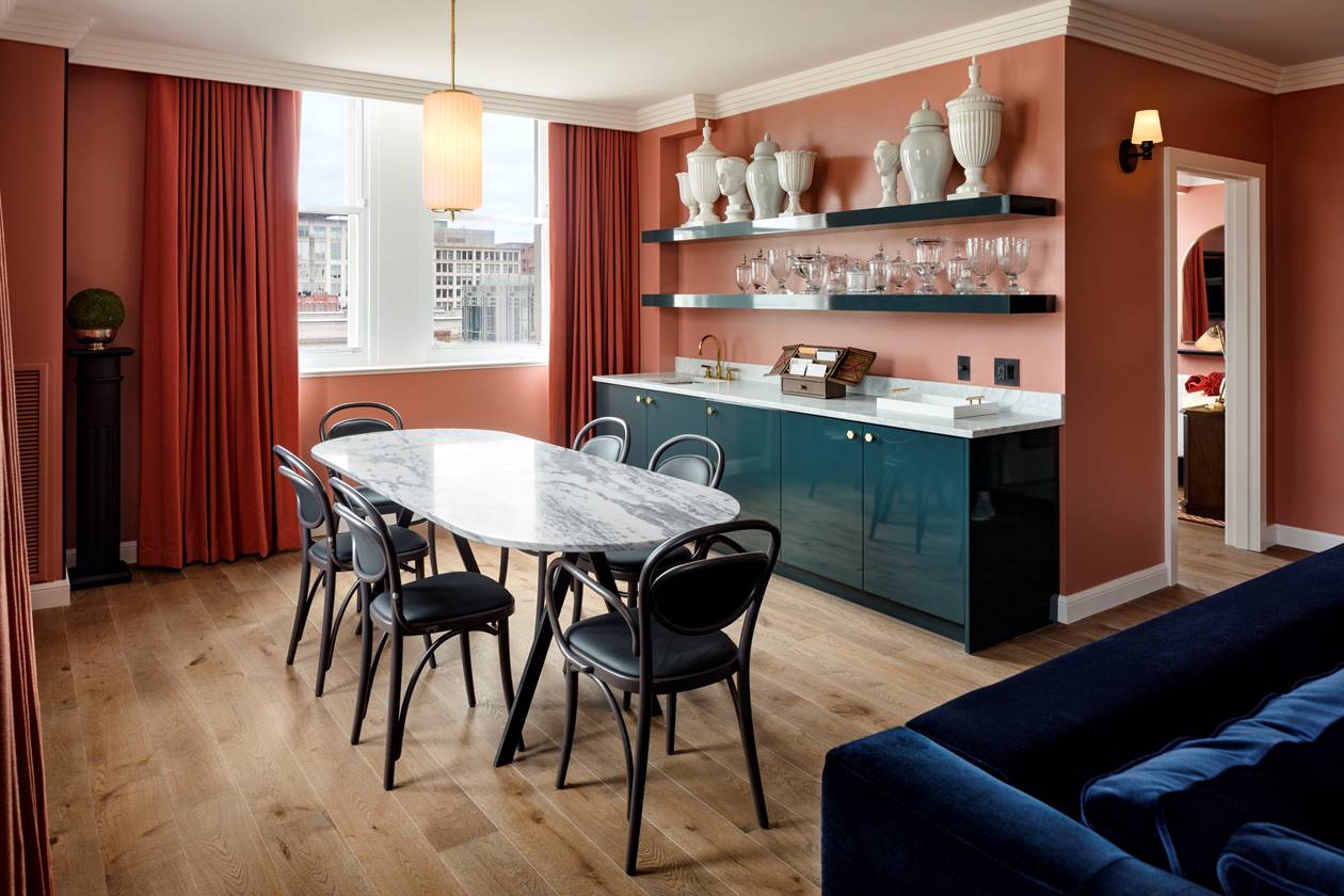 An elegant dining table in the Gallery Suite at Riggs DC, with sophisticated decor and marble art pieces on the shelves.