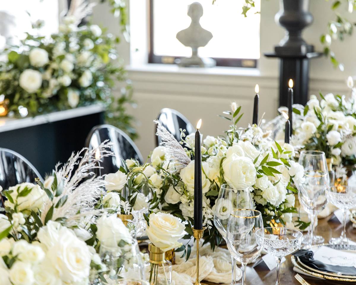 Table set for a wedding reception at Riggs DC, with white flowers, black candles, and elegant tableware.